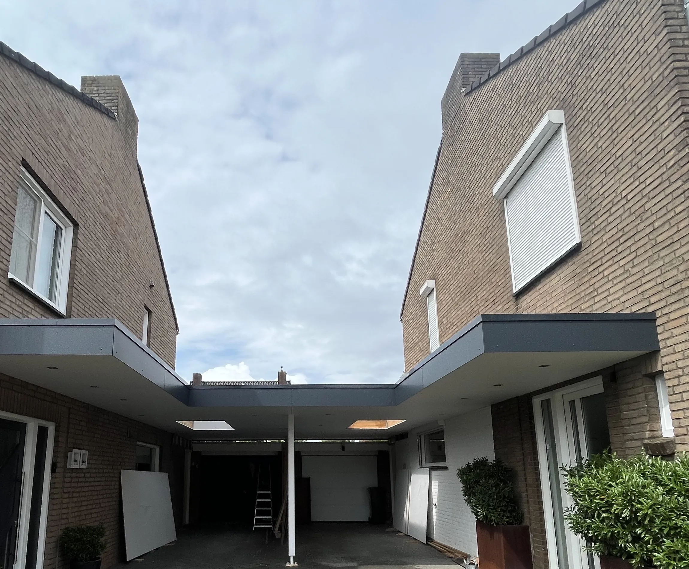 Maatwerk carport tussen twee bestaande woningen.