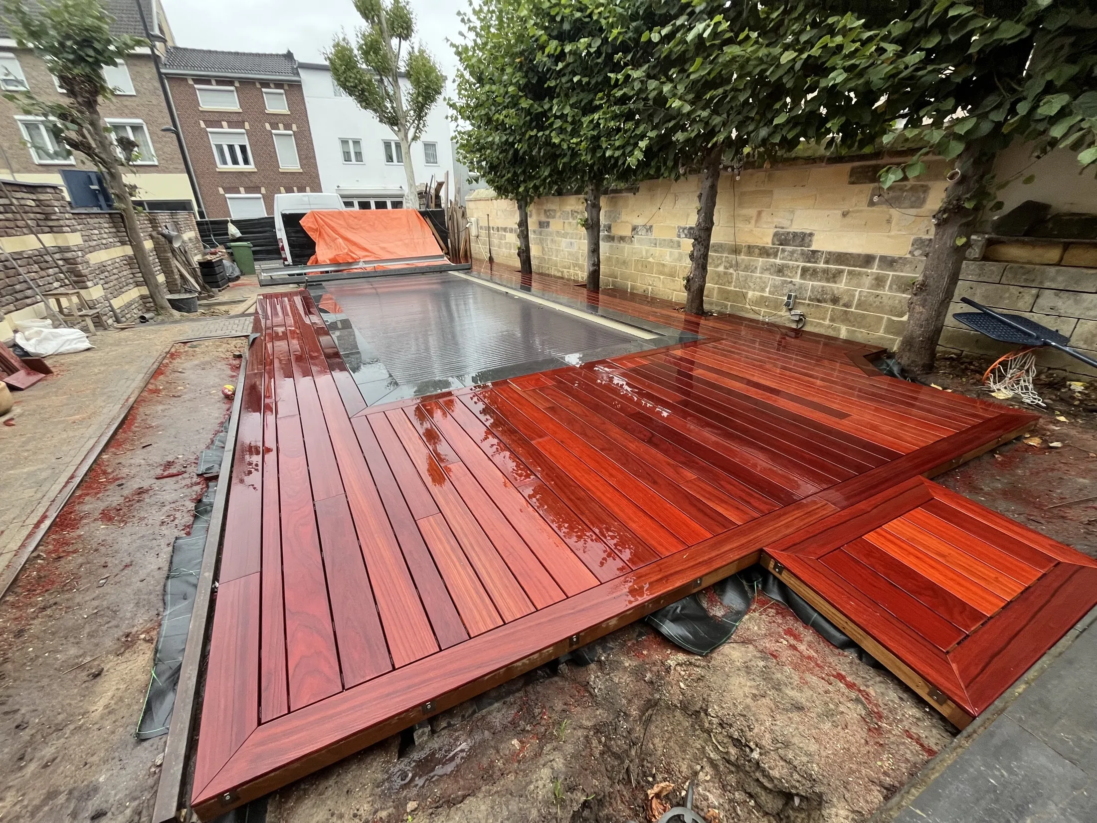 Houten zwembadvlonder op maat rondom een buitenzwembad en bestaande bomen.