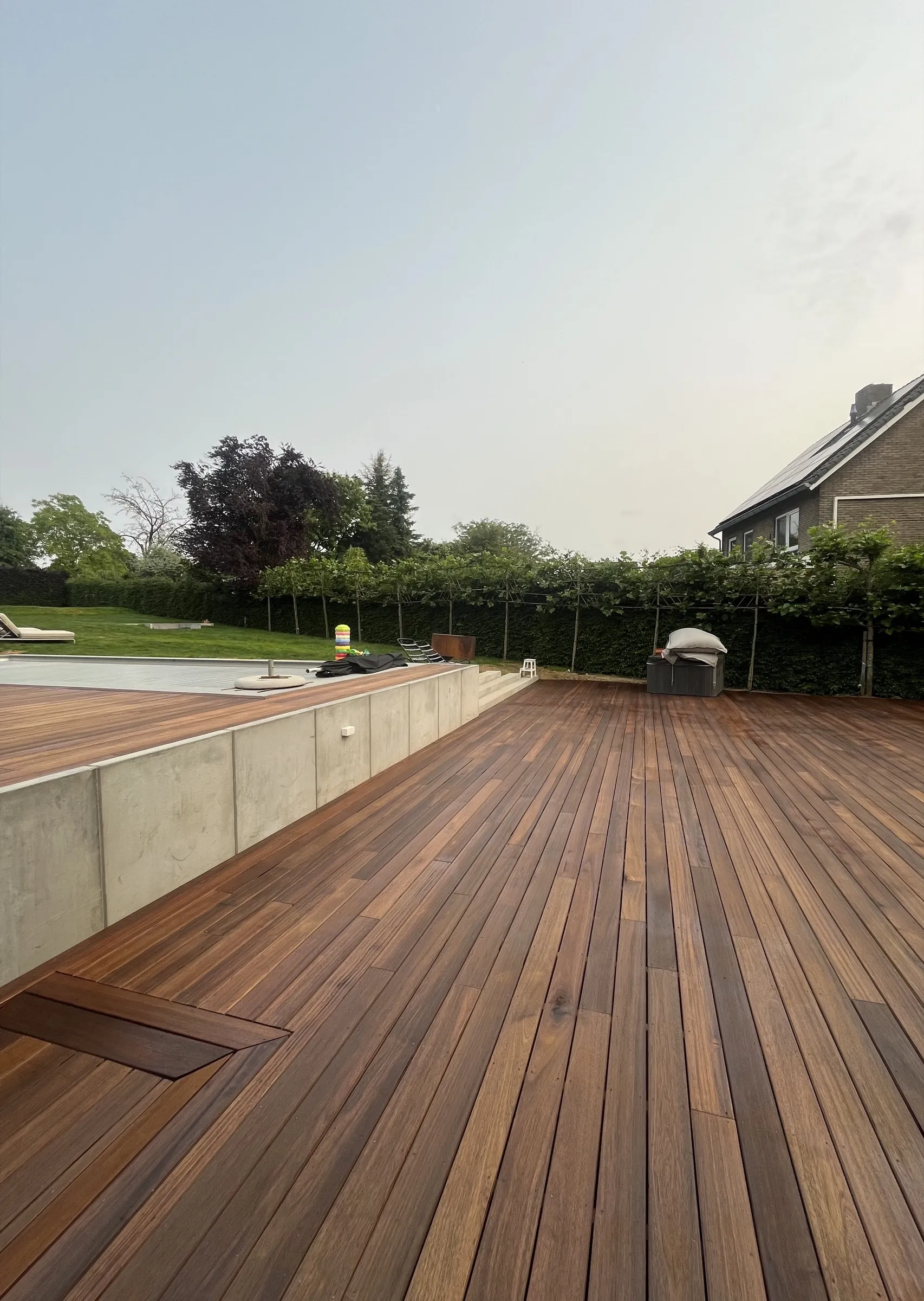 Houten zwembadvlonder die zwembad, terras en tuin met elkaar verbindt.